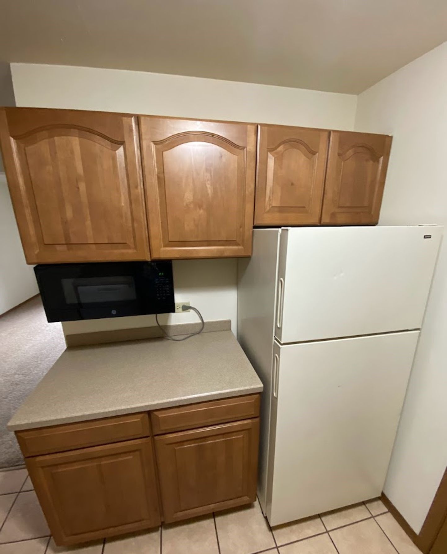 A kitchen with a refrigerator , microwave , and cabinets.