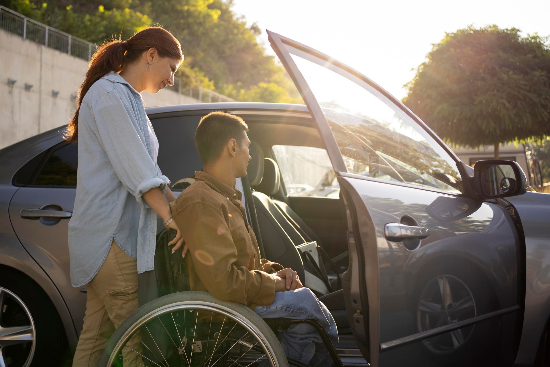 Professional medical assistance personnel helping a passenger with injuries in a wheelchair transition safely into a private transport vehicle.