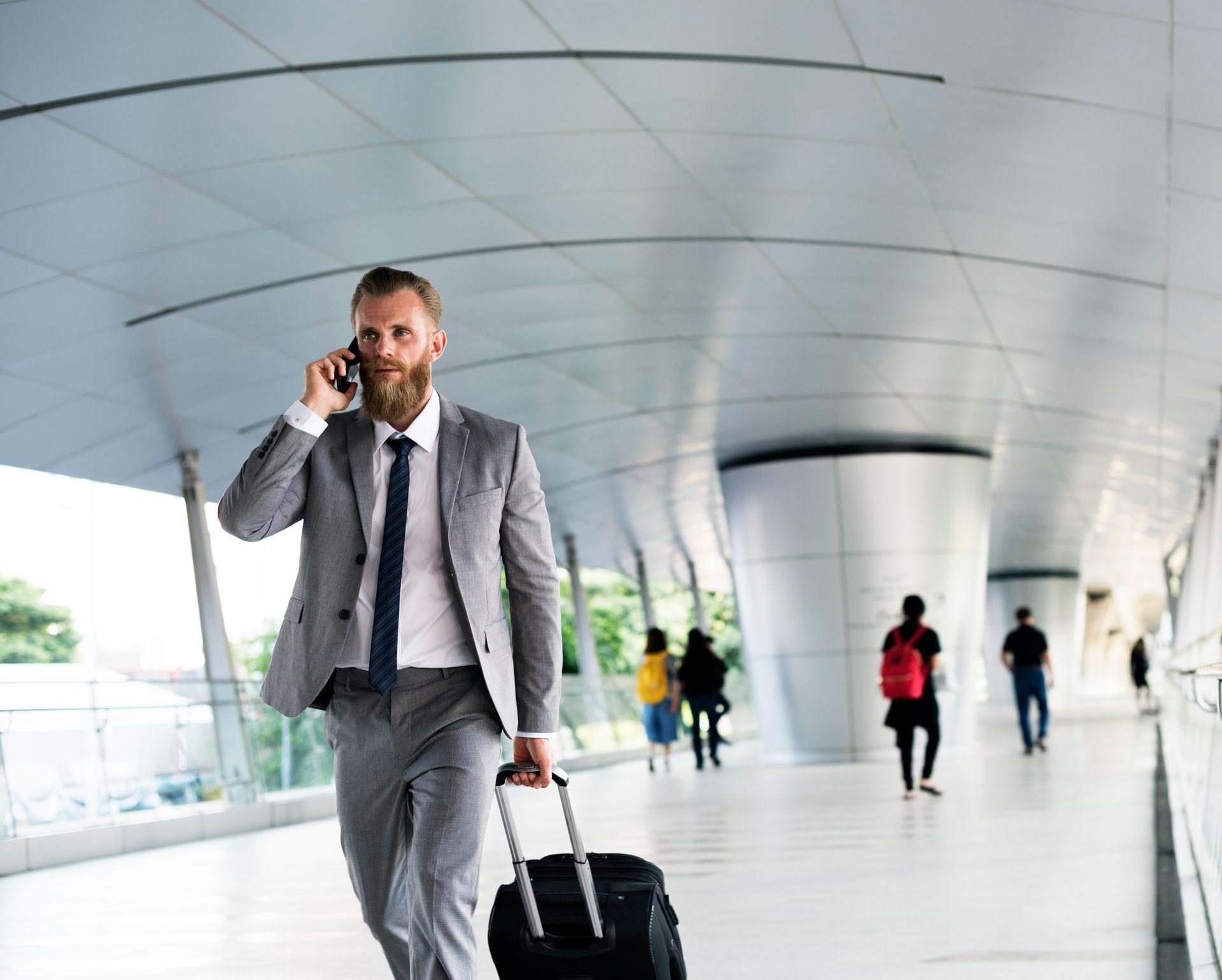 Businessman with luggage walking through the airport, representing a client utilizing our private transfer or executive assistance services.