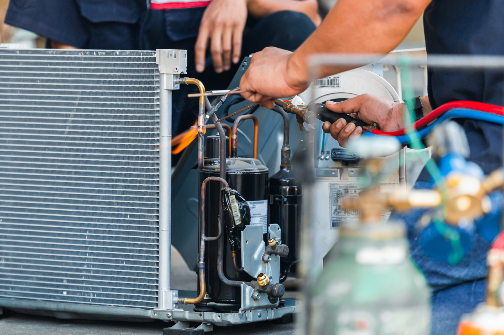 A man is working on an air conditioner with a screwdriver.
