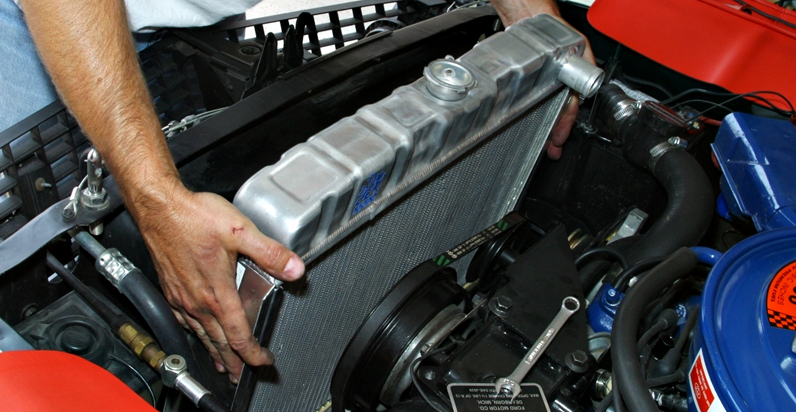 Colocación manual de un radiador de automóvil en el compartimento del motor, junto a mangueras de refrigerante