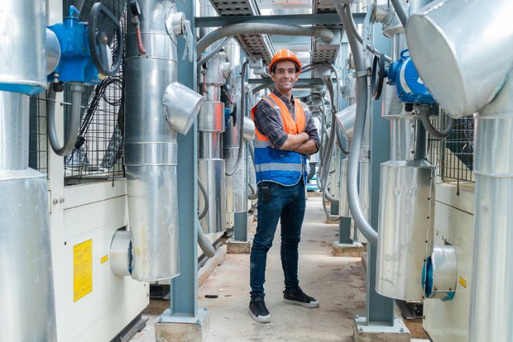 A man is standing in a factory with his arms crossed.