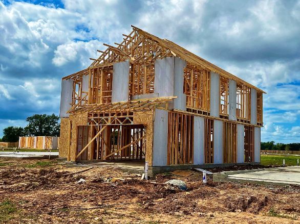 A house is being built in the middle of a dirt field.