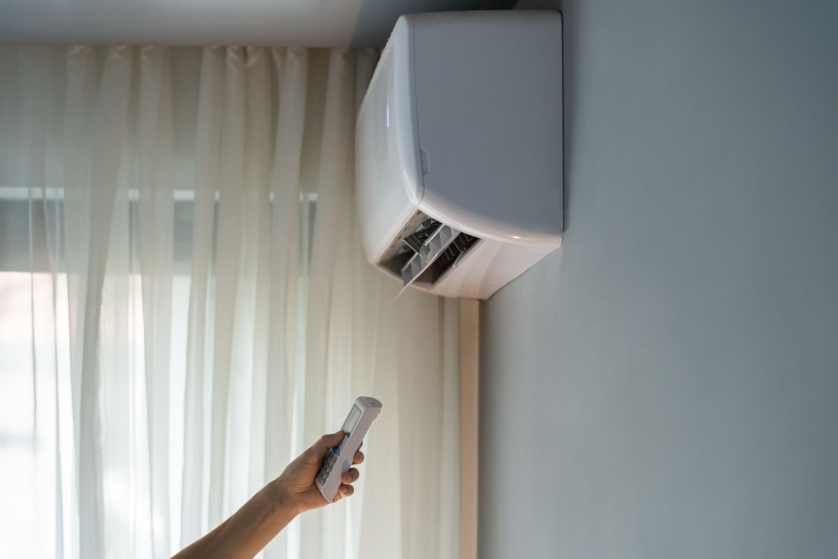 A person is using a remote control to turn on an air conditioner.