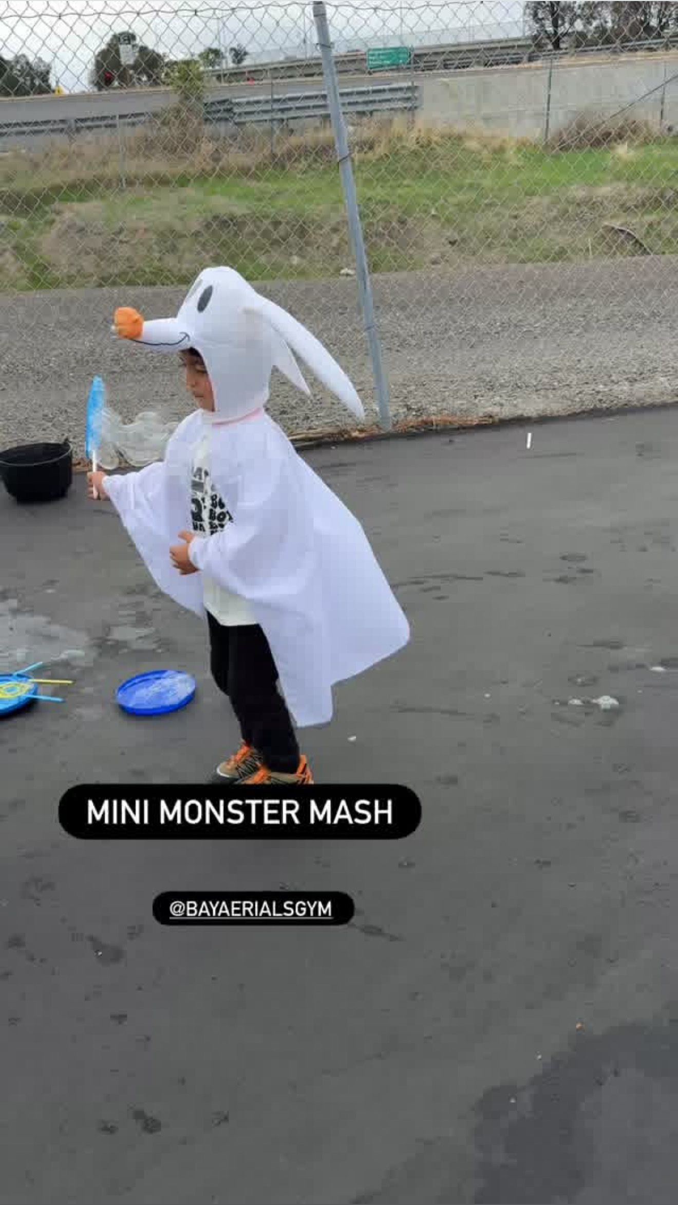 Child in Zero costume playing with bubbles outside.