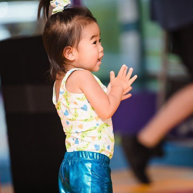 A little girl wearing blue shorts and a white tank top