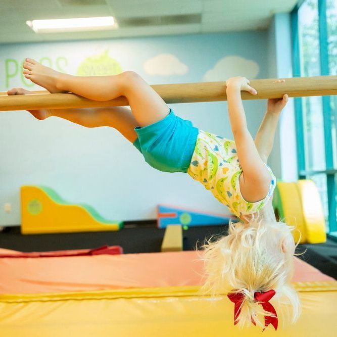 A little girl is doing a handstand on a bar