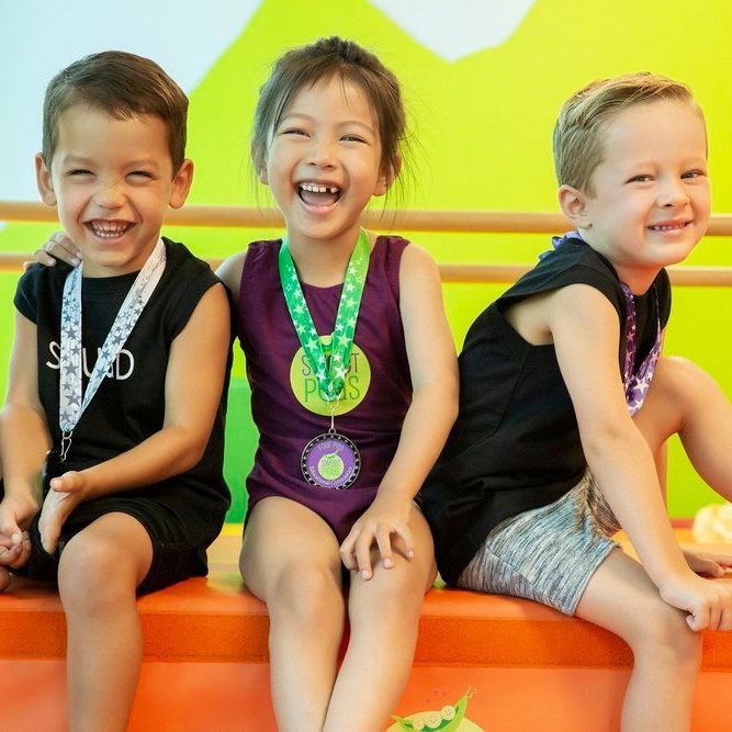 Three children wearing medals are sitting next to each other