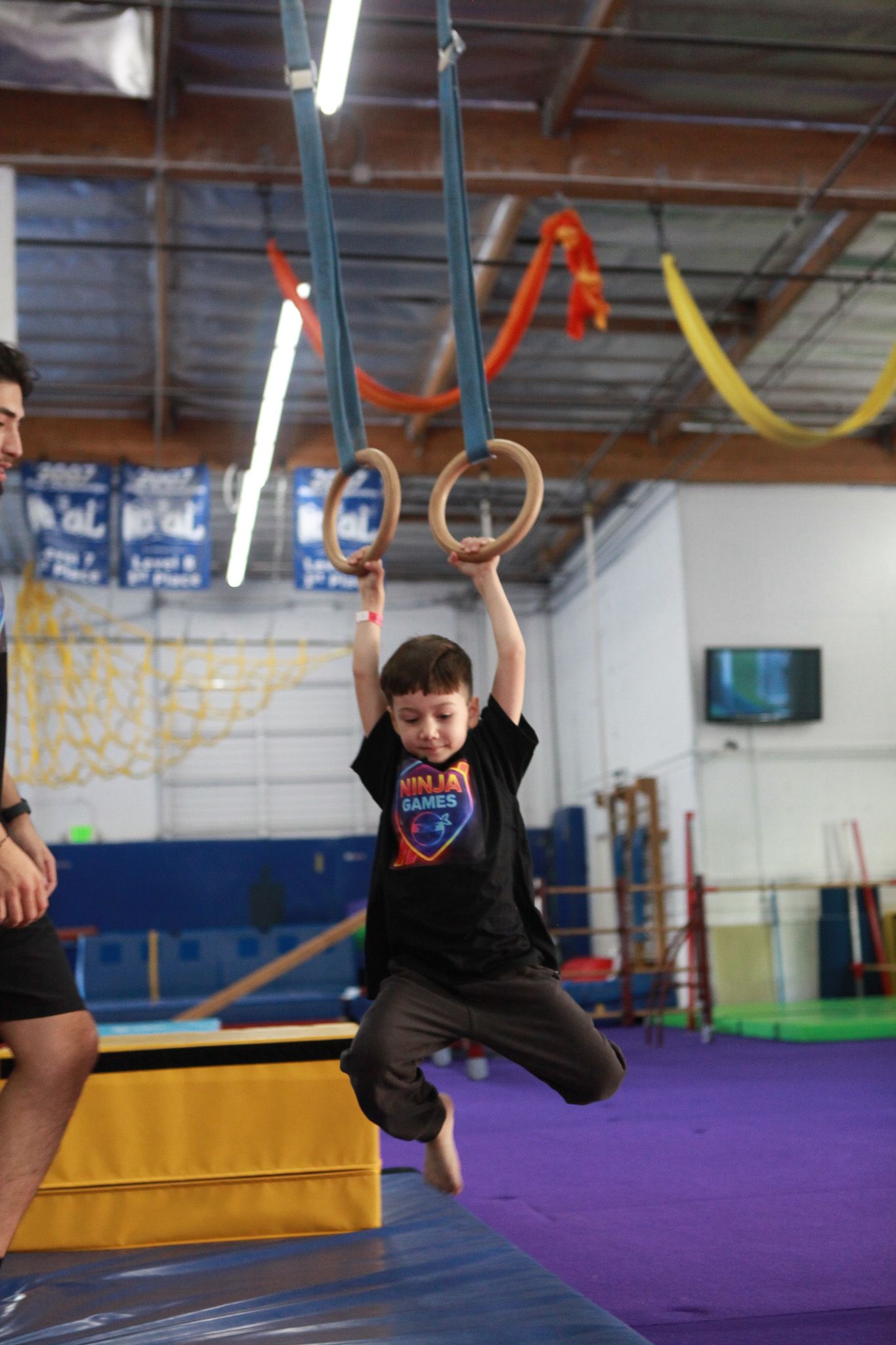 Boy hanging from gymnastic rings in a gym.