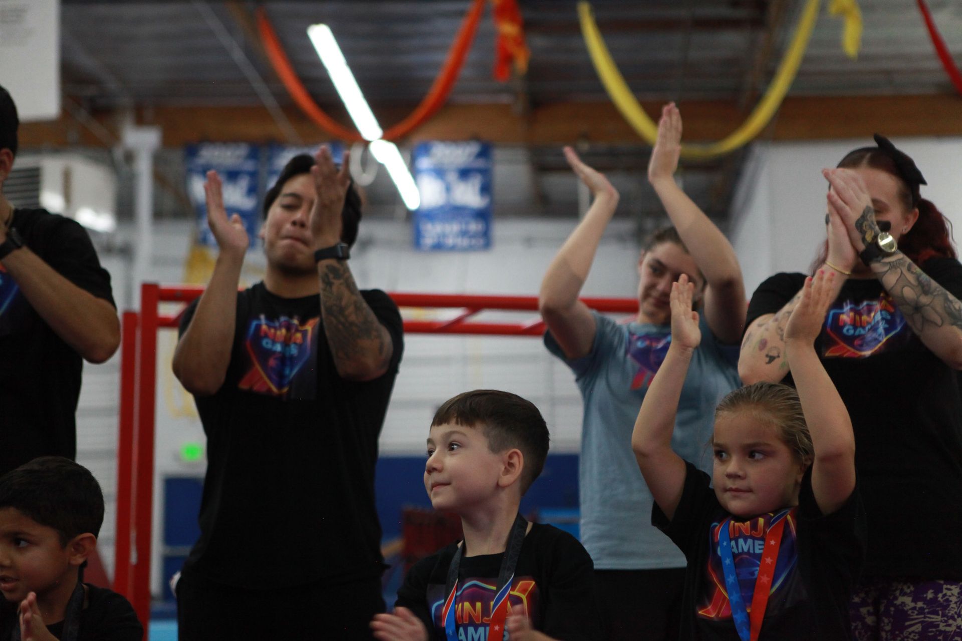 People clapping, celebrating. Indoor sports event setting with colorful decorations.
