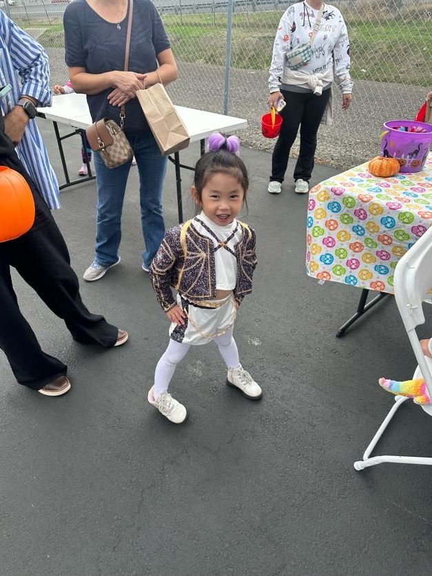 Young child in costume smiling, posing near a table with Halloween decorations.