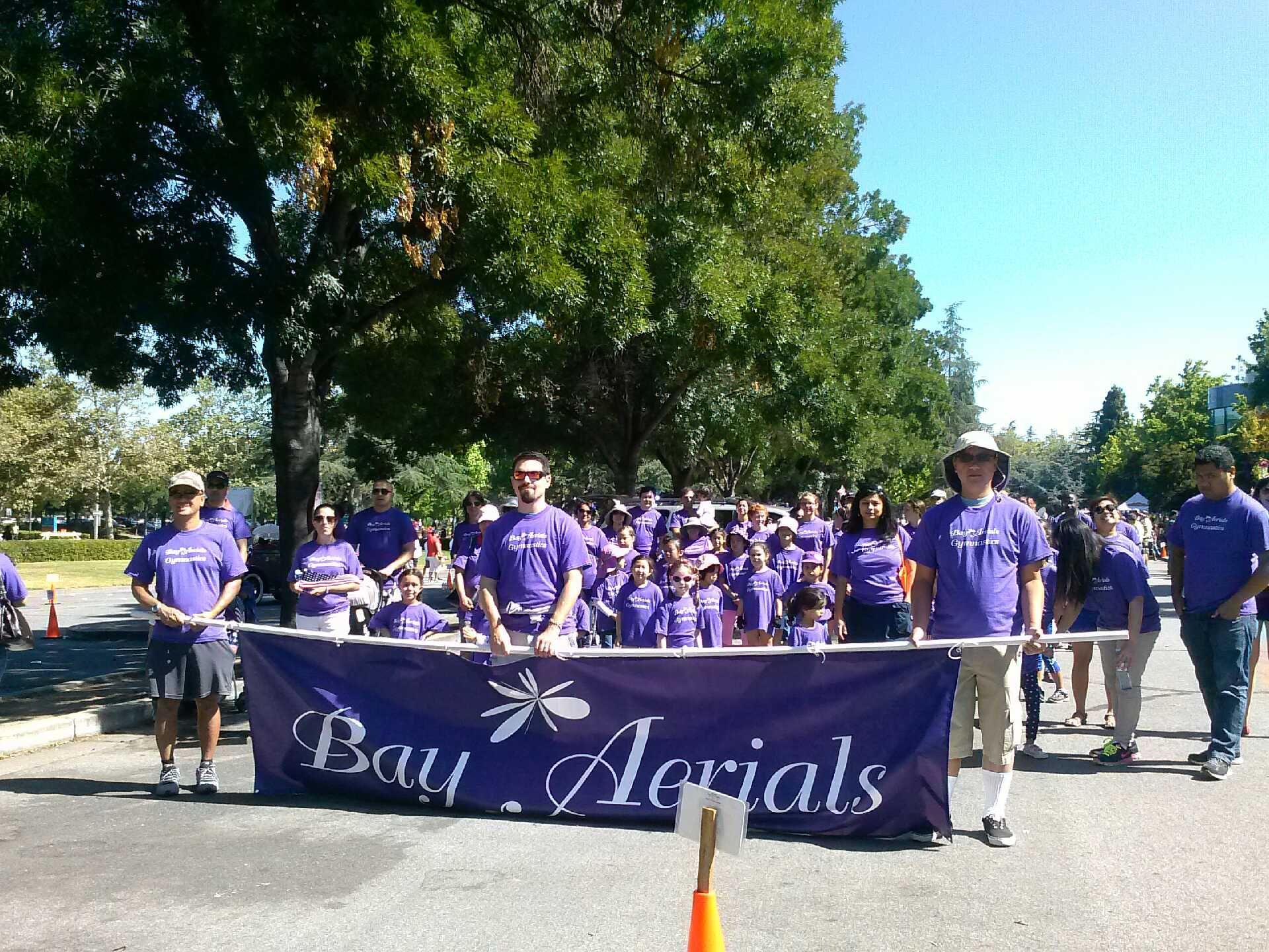 People in purple shirts march with a banner reading 