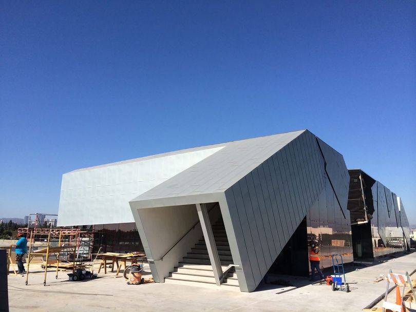 Modern geometric building with angular white facade under construction on a clear day