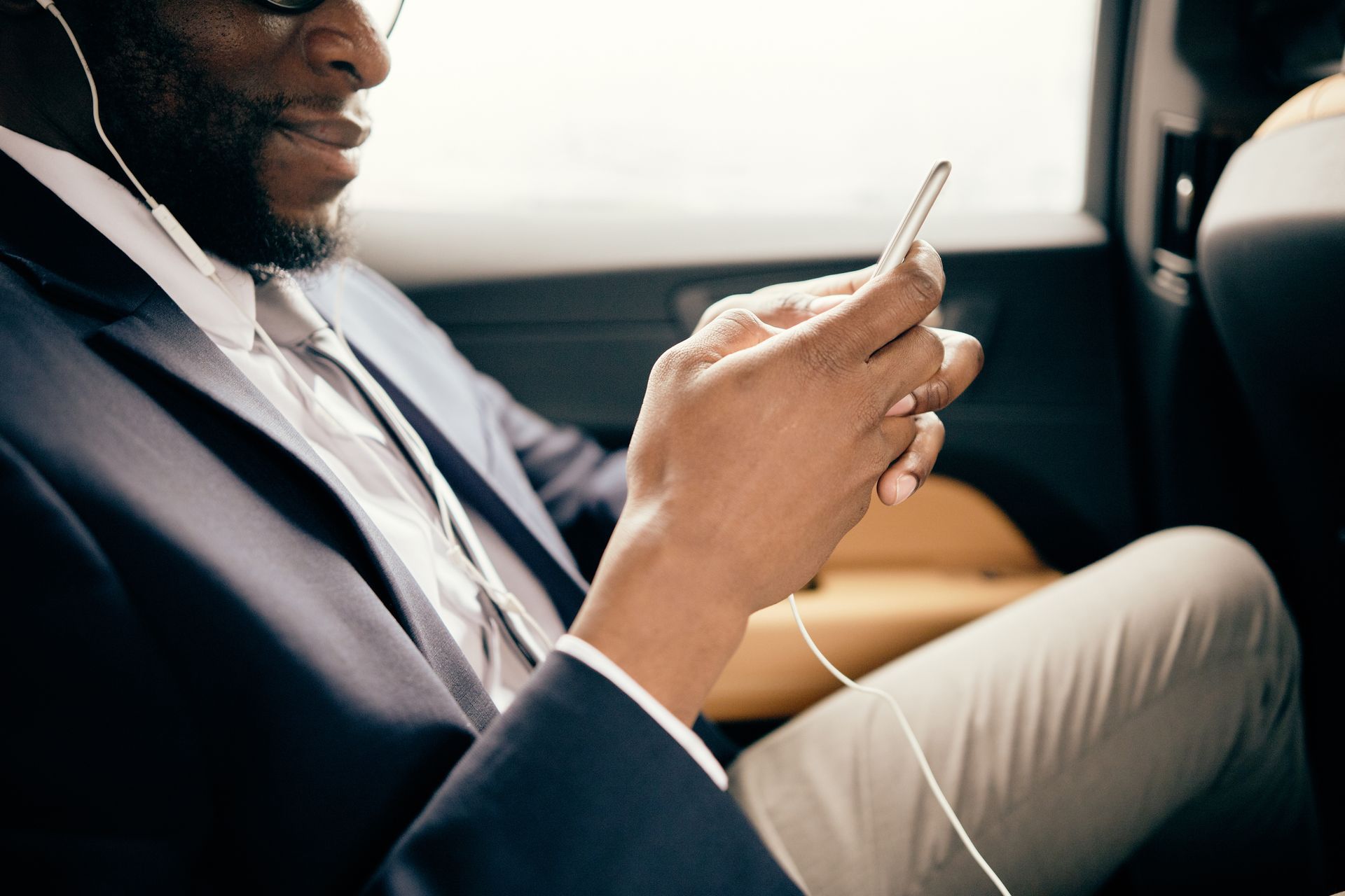 Man in a suit using a smartphone in the back seat of a car