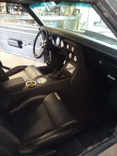 Black sports car interior with steering wheel, gauge cluster, and center console in view