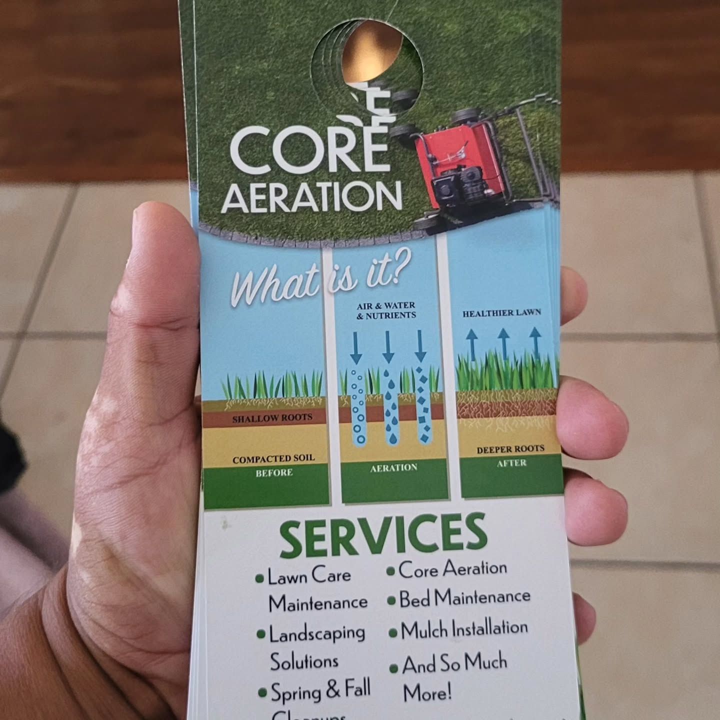 A hand holds a door hanger promoting core aeration and landscaping services, featuring graphics of soil and grass health.
