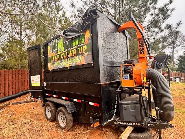 A black leaf vacuum trailer with a bright orange Scag engine parked outdoors on a dirt lot.
