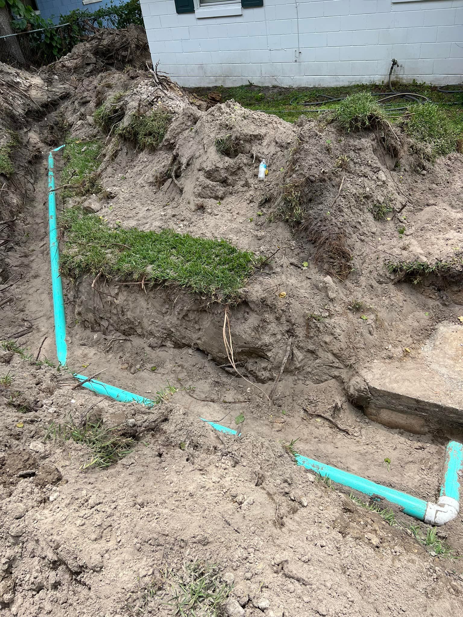 Blue PVC pipes installed in trenches dug in dirt.