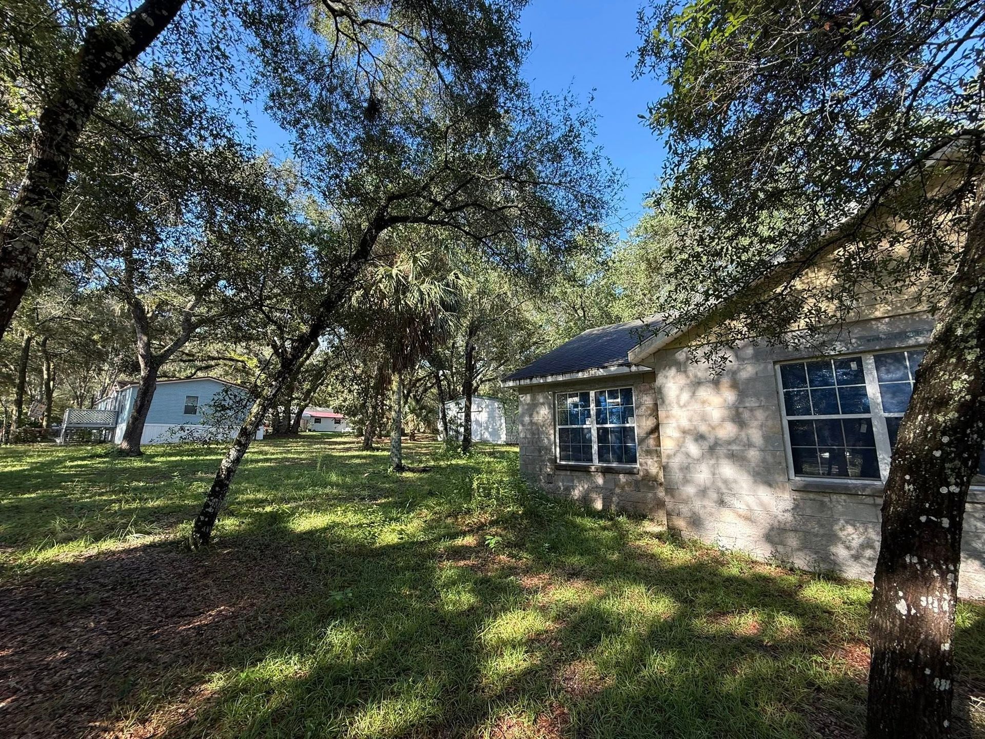 Stone building surrounded by trees and grass, on a sunny day.