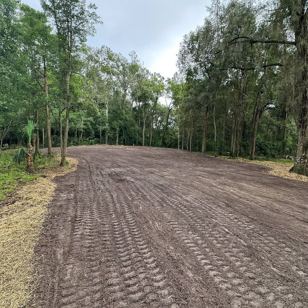 A small house with bare earth in front; a large tree stump is in the foreground.