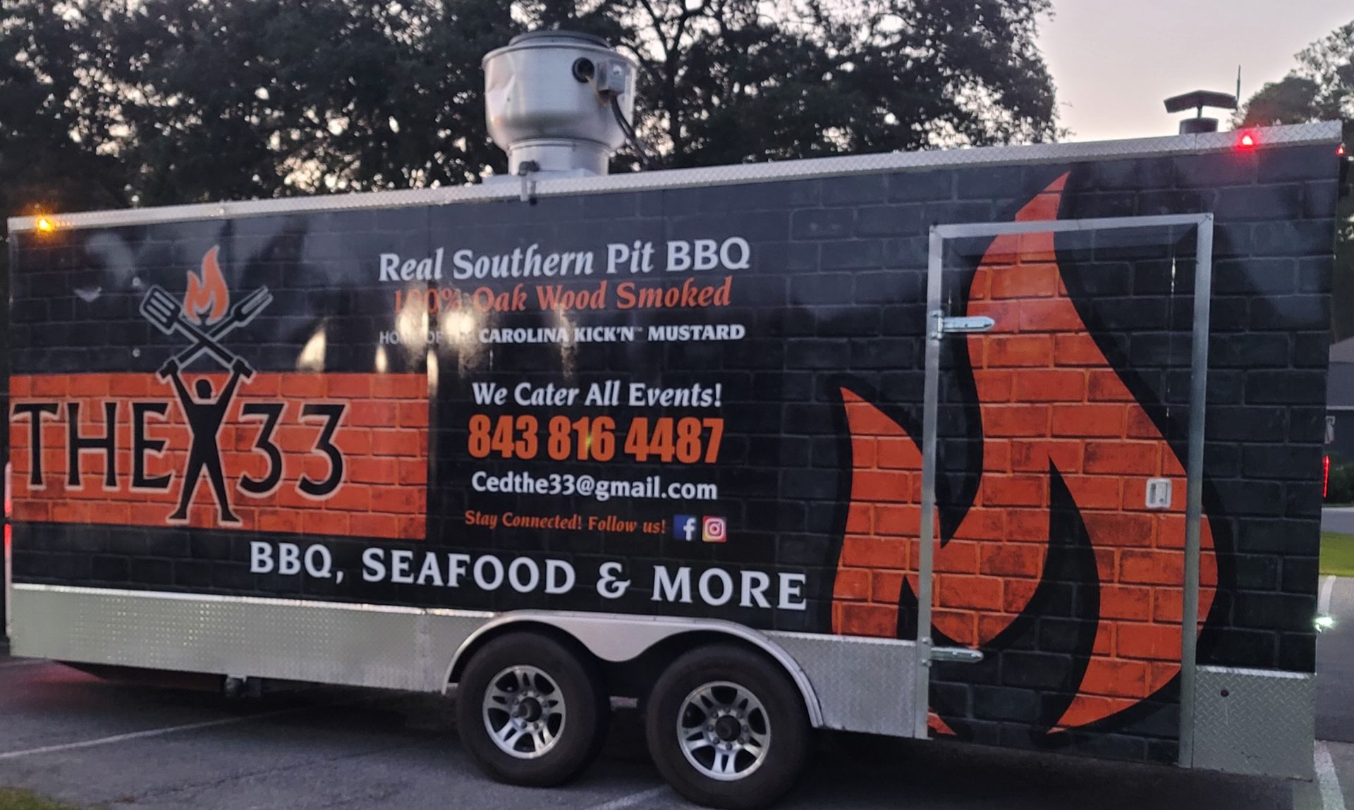 A black food trailer with red brick patterns, fire graphics, and text for