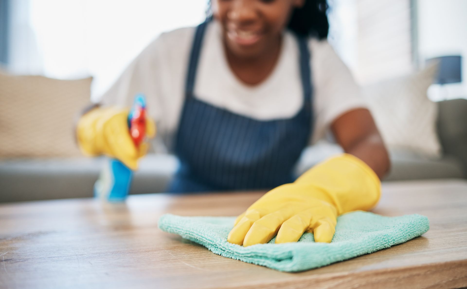 Two people cleaning an office: one mopping, the other wiping a desk, both wearing aprons and gloves. Two people cleaning an office: one mopping, the other wiping a desk, both wearing aprons and gloves.