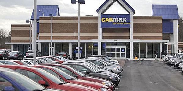 CarMax car dealership with rows of cars parked in front of the building. CarMax car dealership with rows of cars parked in front of the building.