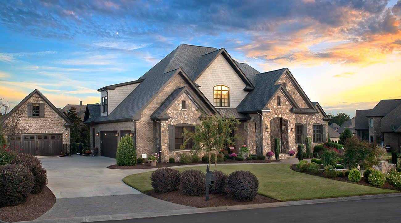 A large house is sitting on top of a lush green lawn in a residential neighborhood.