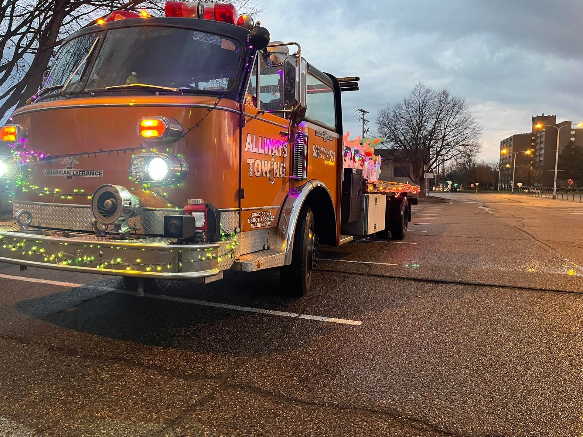 A fire truck with christmas lights on it is parked in a parking lot.