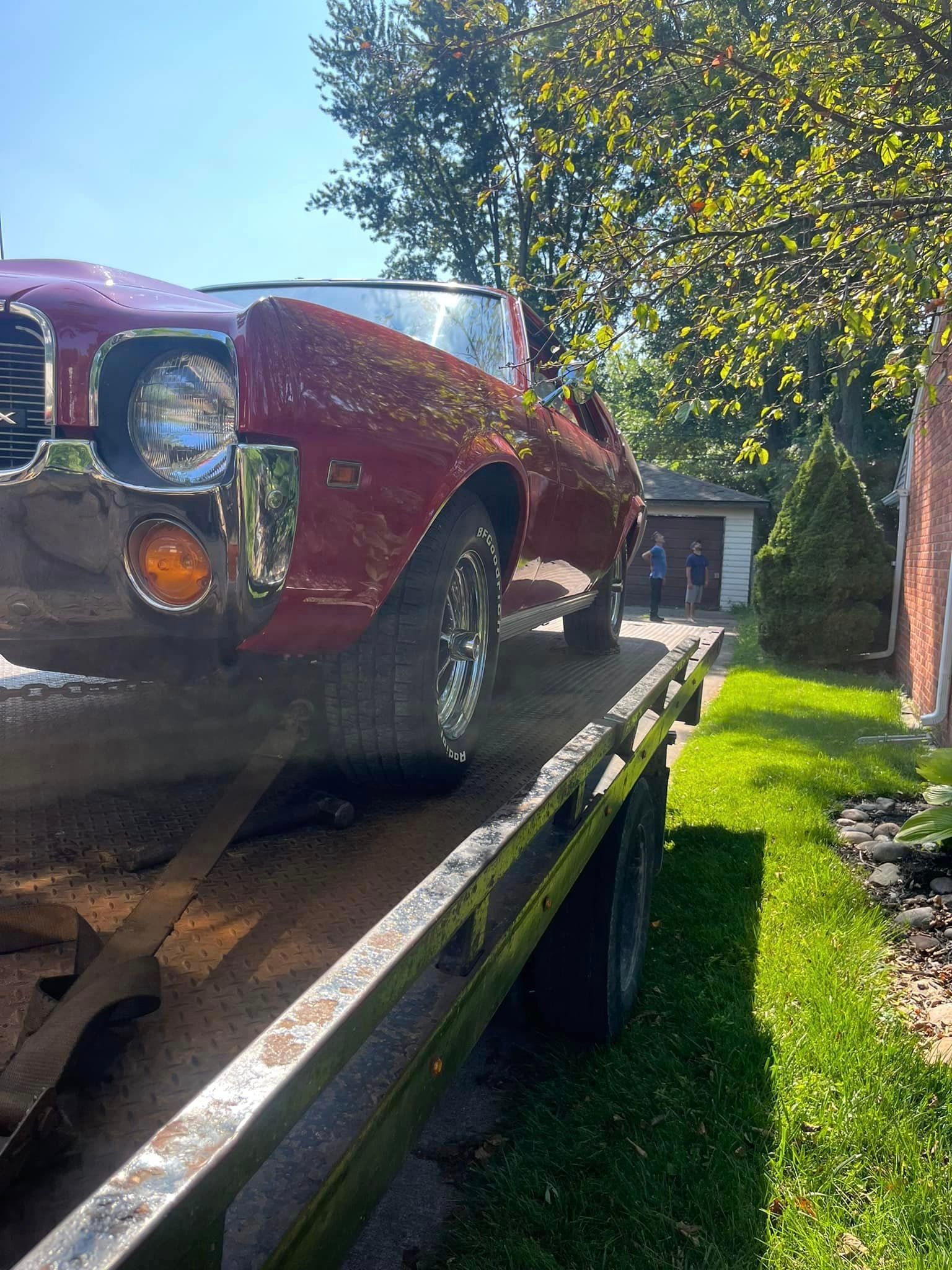 A red car is sitting on top of a tow truck.
