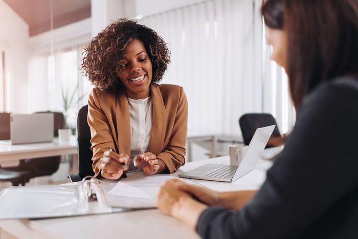 A woman is sitting at a table talking to another woman.