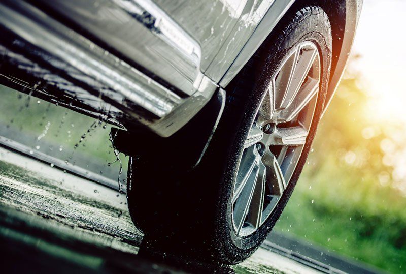Car Driving in the Rain. Modern Rain Summer Season Tires on the Wet Pavement. Closeup Aquaplaning Photo.