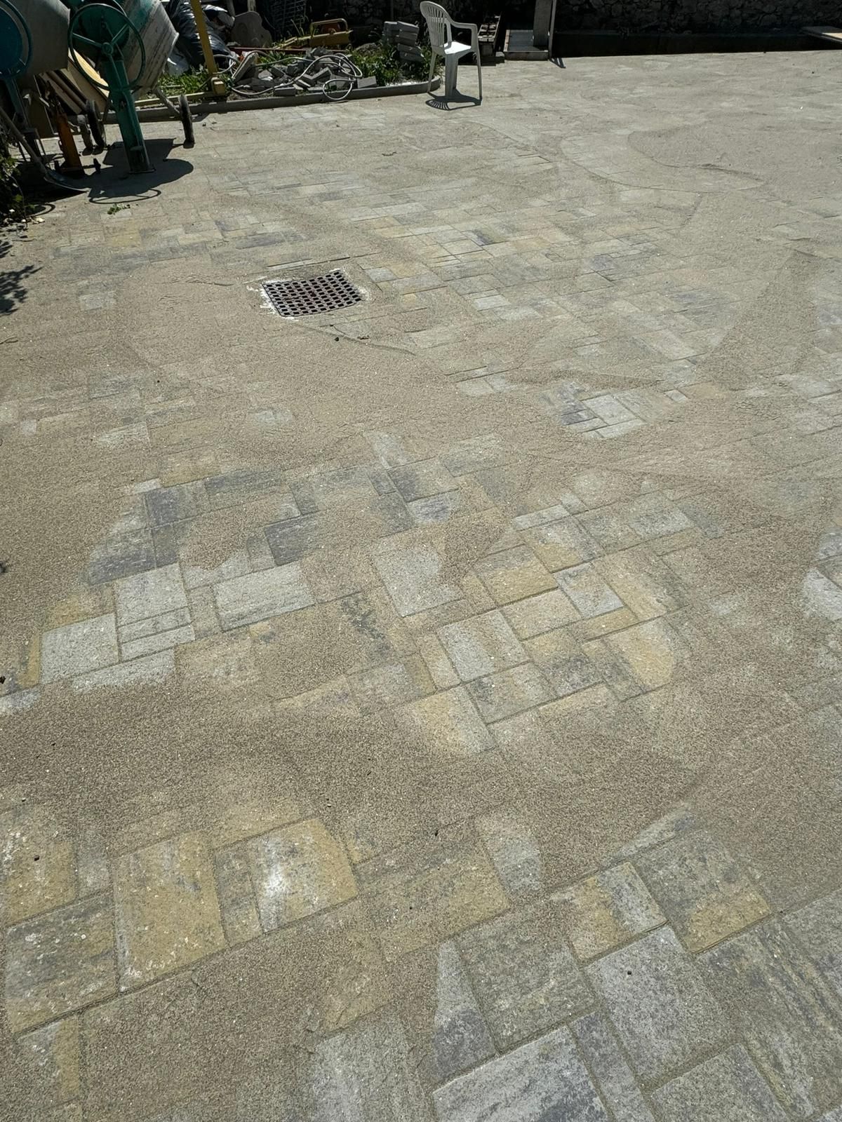 Un patio pavimentato in pietra con scarico, circondato da mobili da esterno, in un soleggiato cortile residenziale.