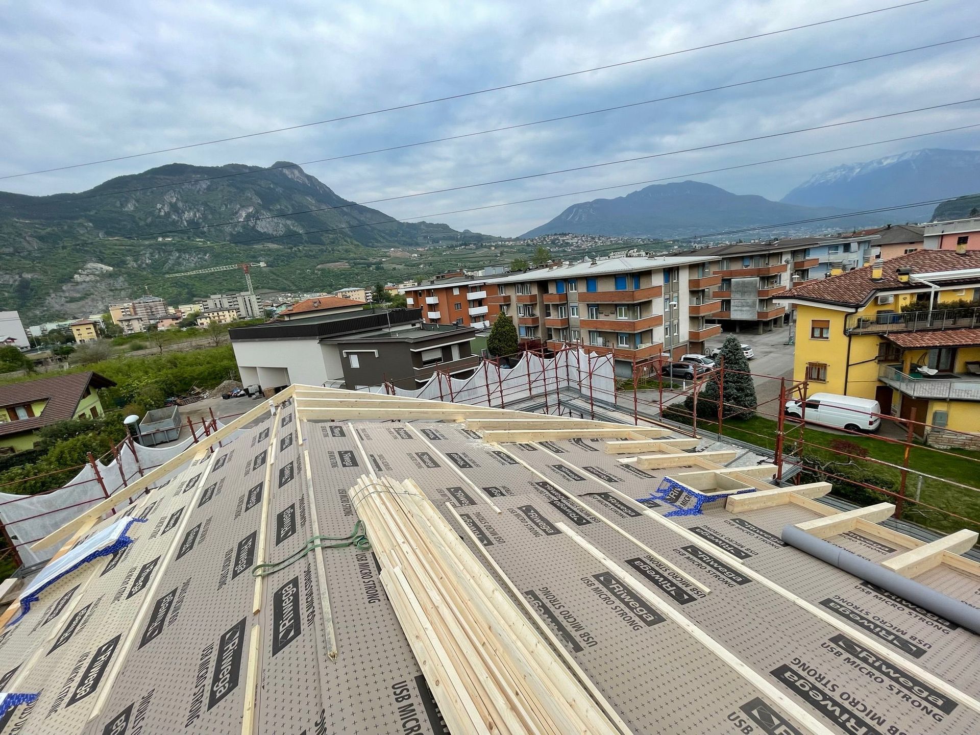 Vista dall'alto di un tetto residenziale in costruzione, con l'etichettatura del sottostrato protettivo sopra le travi di legno.