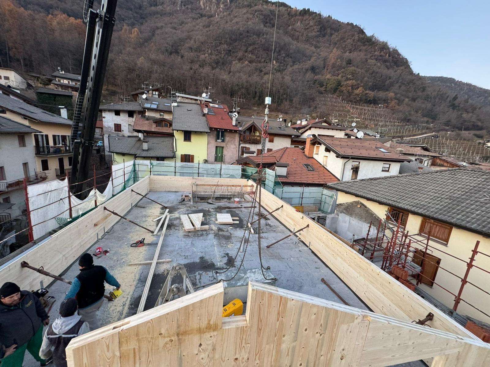 In un villaggio di montagna, alcuni operai edili assemblano la struttura in legno del tetto di un edificio.