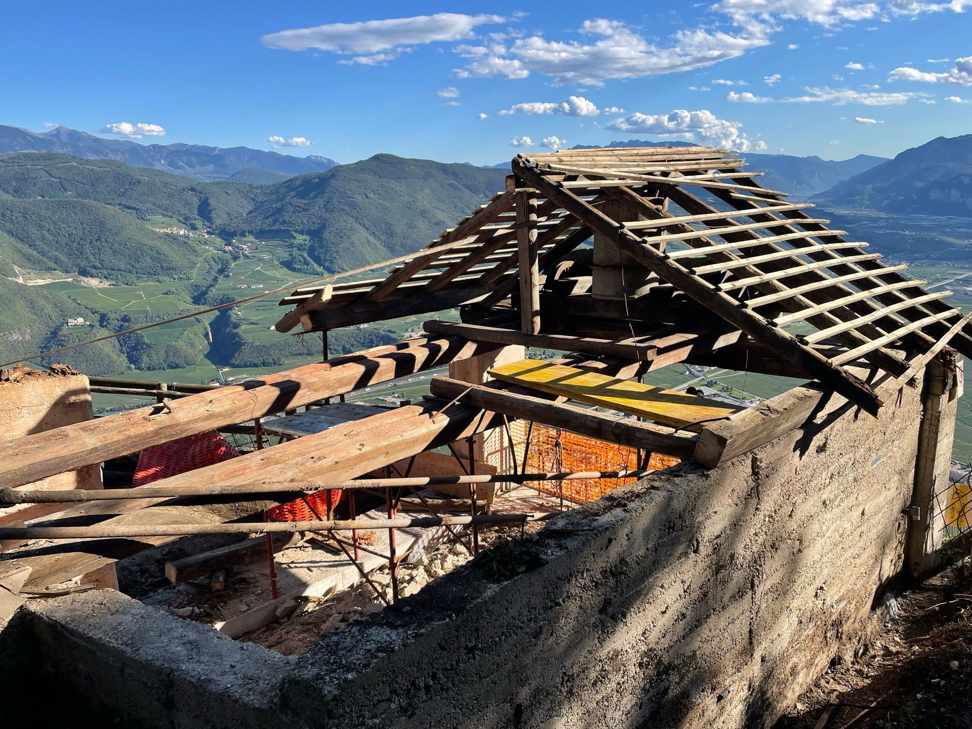 Una struttura in pietra fatiscente, con un tetto a traliccio in legno, si erge affacciata su una valle di verdi montagne.