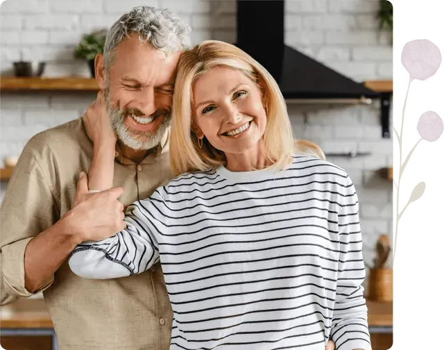 A man and a woman are posing for a picture in a kitchen.
