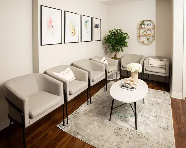 A waiting room with a row of chairs and a table.