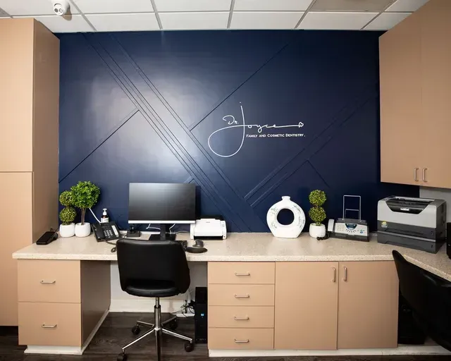 An office with a blue wall and a desk with a computer on it