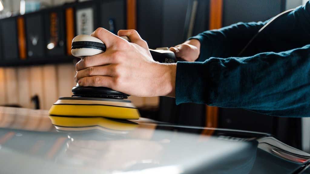 A man is polishing a car with a machine.