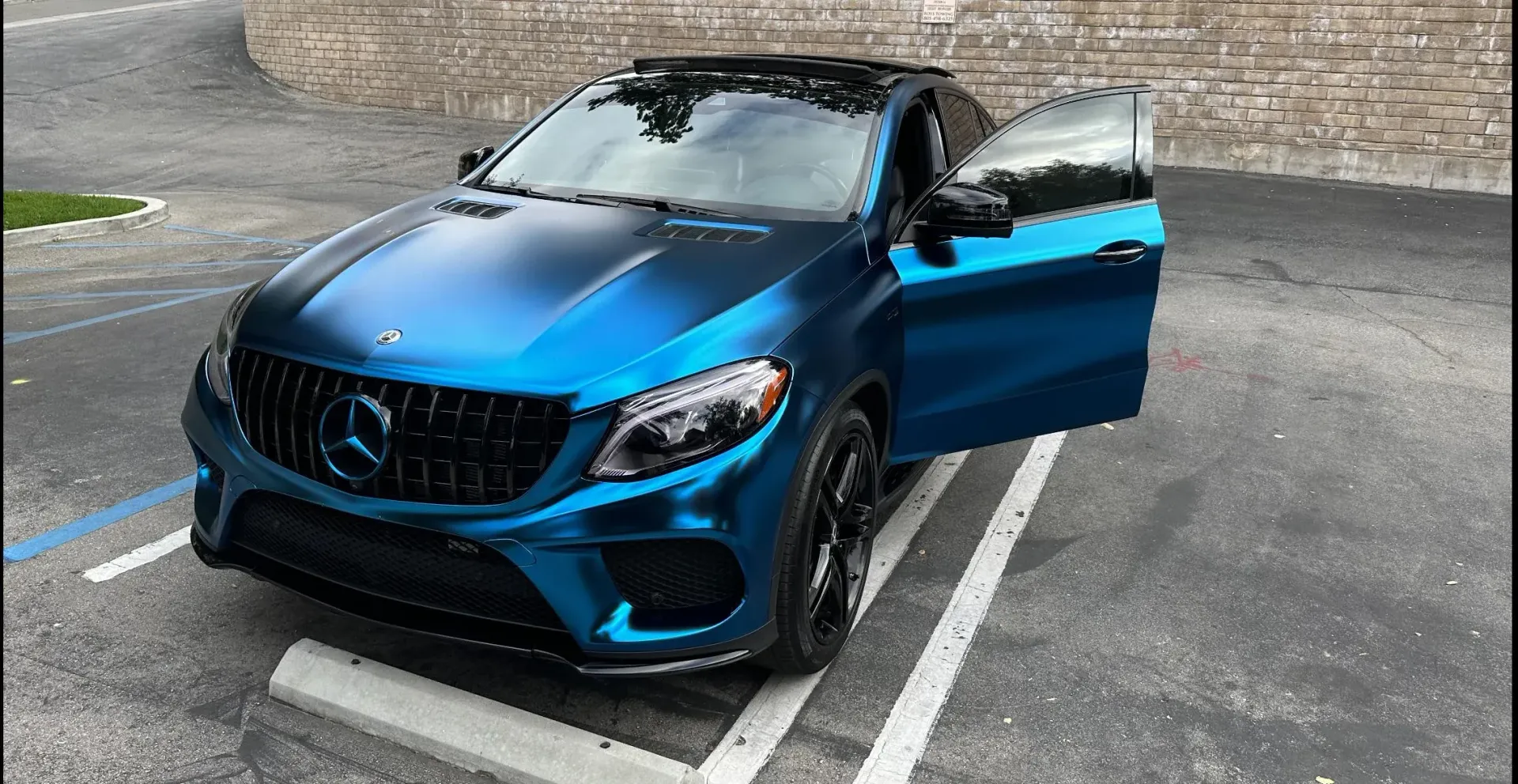 A blue mercedes benz gle is parked in a parking lot with its doors open.