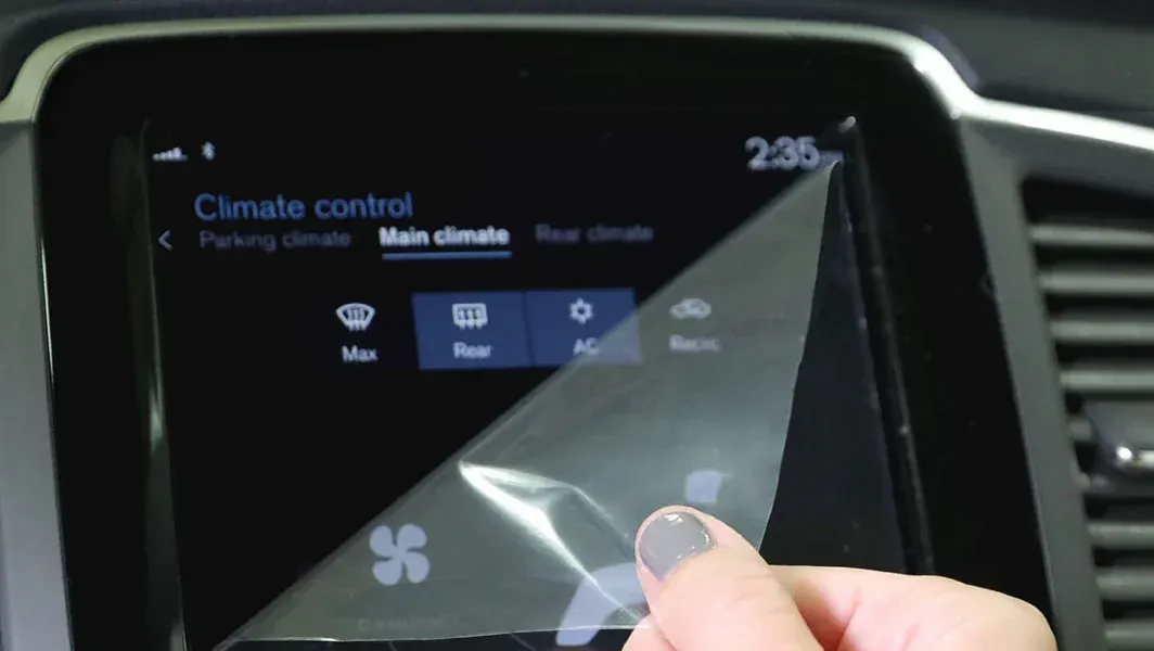 A person is putting a screen protector on a car dashboard