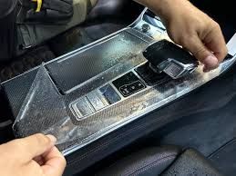 A person is applying a plastic protector to the dashboard of a car.