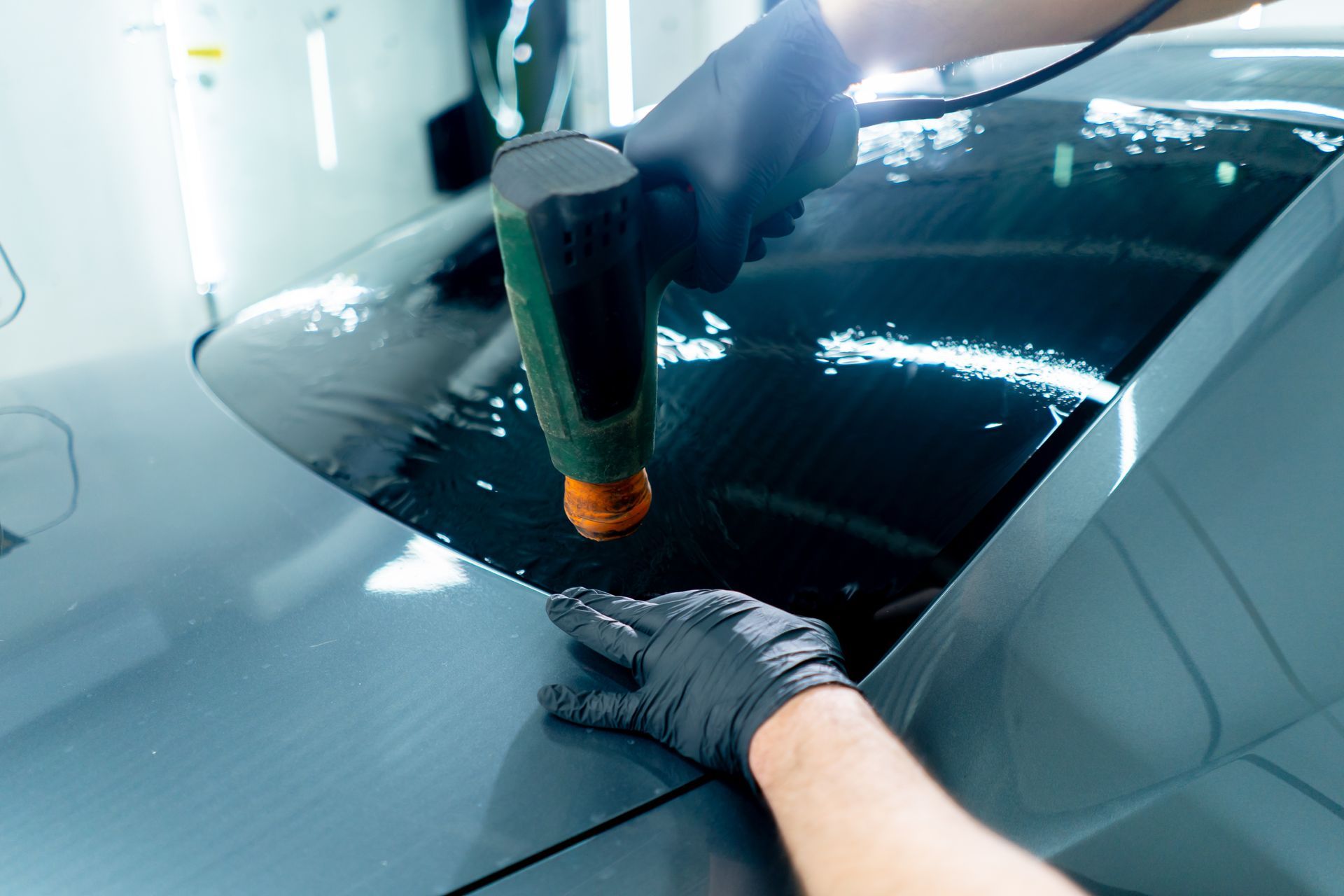 A person is applying window tinting to a car windshield.