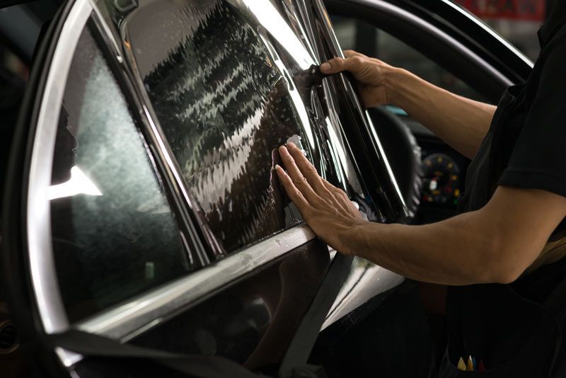 A person is applying window tinting to a car window.