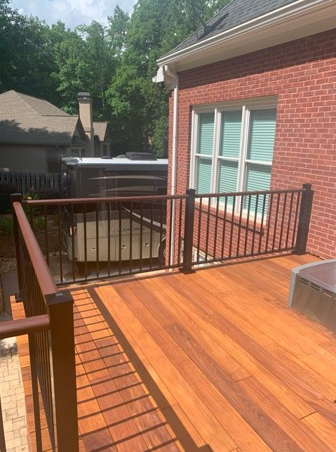 A wooden deck with a metal railing in front of a brick house in North Georgia