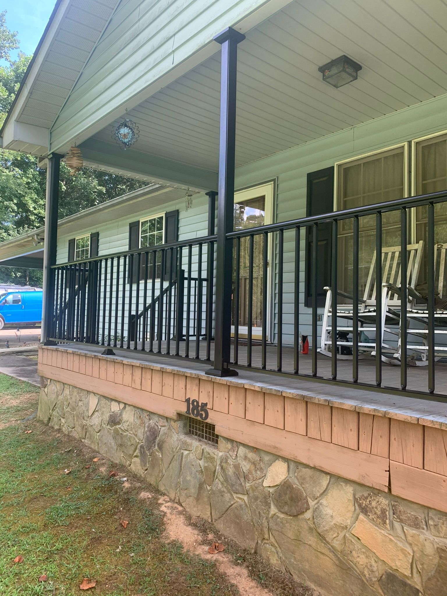 A white house with a custom porch and rocking chairs on it.