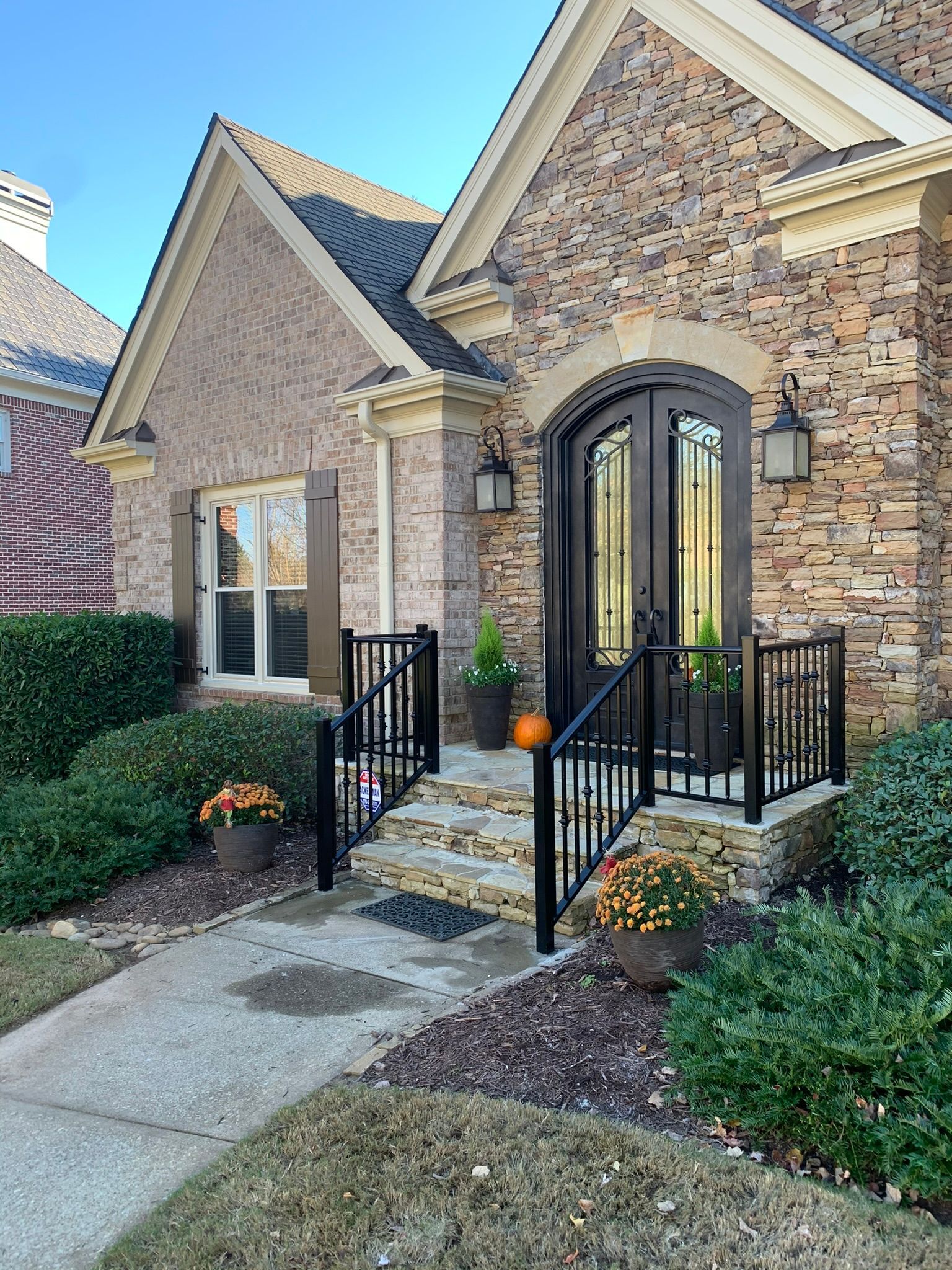A large brick house with a black front door and stairs leading up to it.