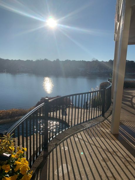 A view of a lake from a balcony with a black railing
