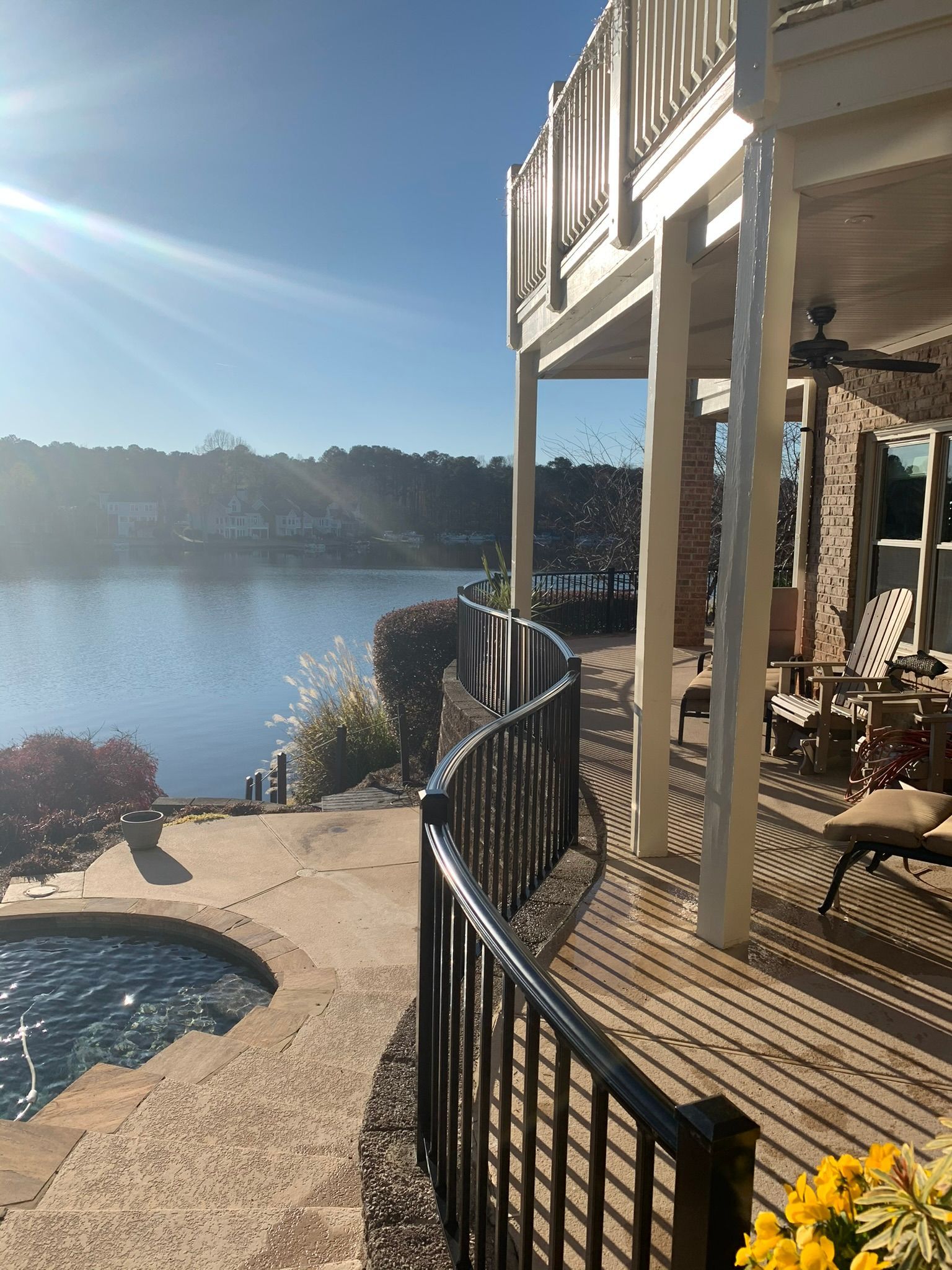 A large house with a large deck overlooking a lake.